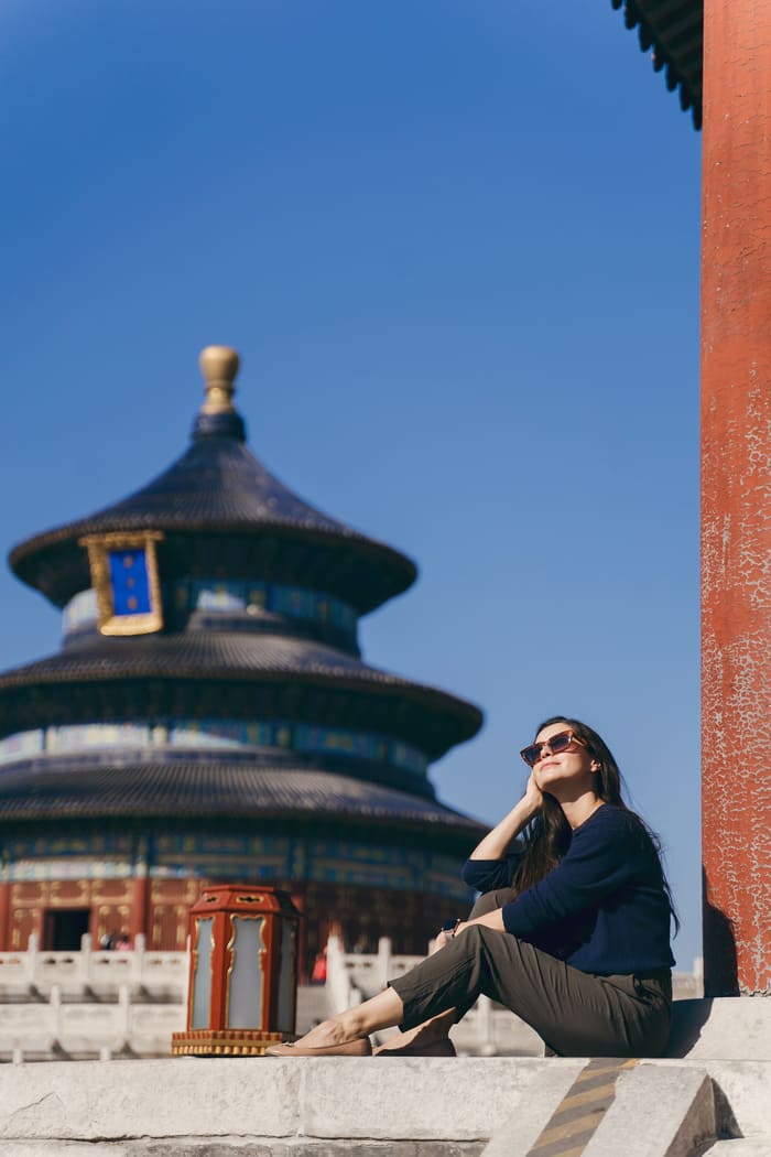 Mujer turista sentada y al fondo un templo chino en Beijing